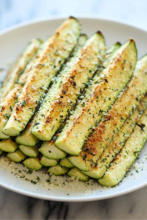 Crispy baked zucchini spears coated in golden parmesan cheese and herbs on a serving platter